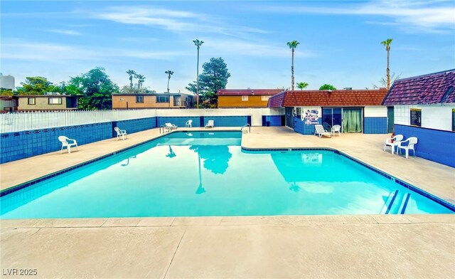 community pool with a patio and fence
