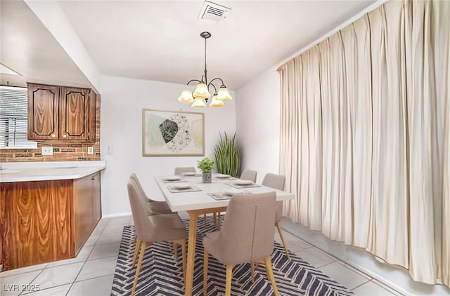 dining space with a notable chandelier, visible vents, and light tile patterned flooring
