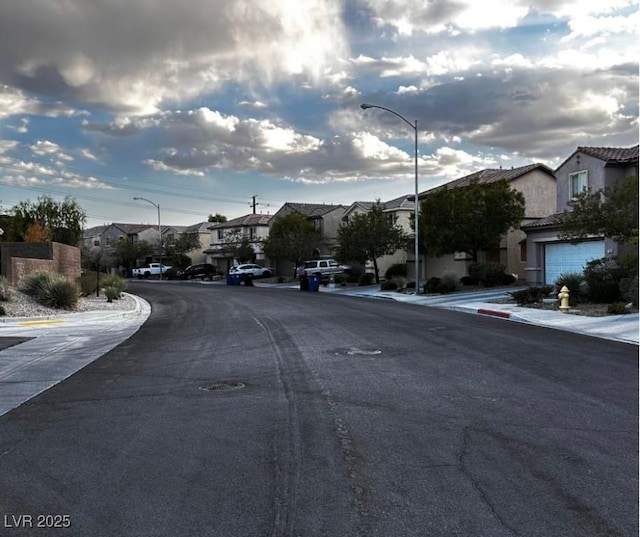 view of street featuring street lights, a residential view, curbs, and sidewalks