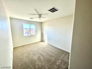 empty room with carpet, visible vents, and a ceiling fan
