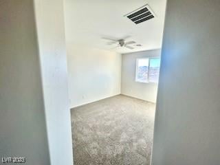 carpeted spare room featuring a ceiling fan and visible vents