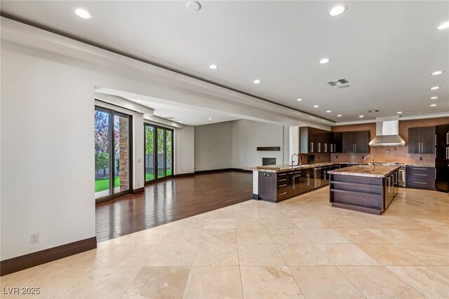 9501 Balatta Canyon Ct, Las Vegas, NV 89144 - kitchen with visible vents, wall chimney exhaust hood, open floor plan, baseboards, and dark brown cabinets