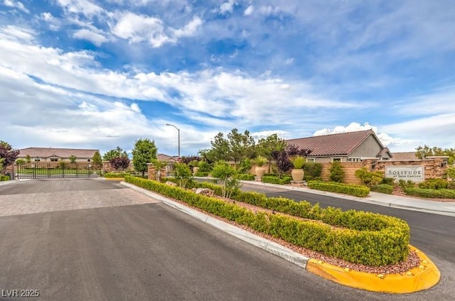 8257 Skye Peak St, Las Vegas, NV 89166 - view of asphalt road featuring street lighting, curbs, a gated entry, a gate, and sidewalks