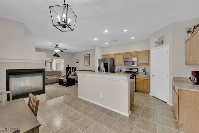 kitchen featuring light brown cabinetry, light tile patterned floors, ceiling fan with notable chandelier, light countertops, and appliances with stainless steel finishes