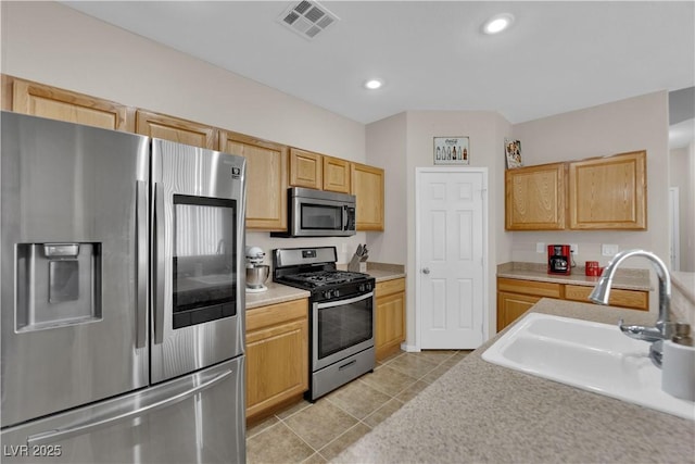 kitchen with light tile patterned floors, a sink, stainless steel appliances, visible vents, and light countertops