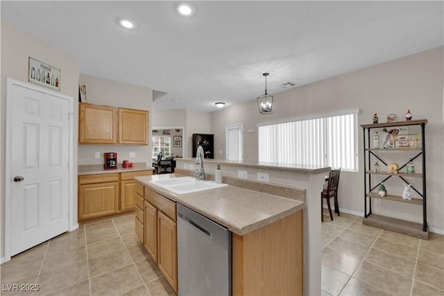 kitchen featuring light countertops, stainless steel dishwasher, light brown cabinets, and a sink