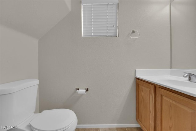 half bath with vaulted ceiling, vanity, and toilet