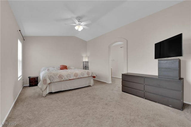 carpeted bedroom with ceiling fan, lofted ceiling, arched walkways, and baseboards