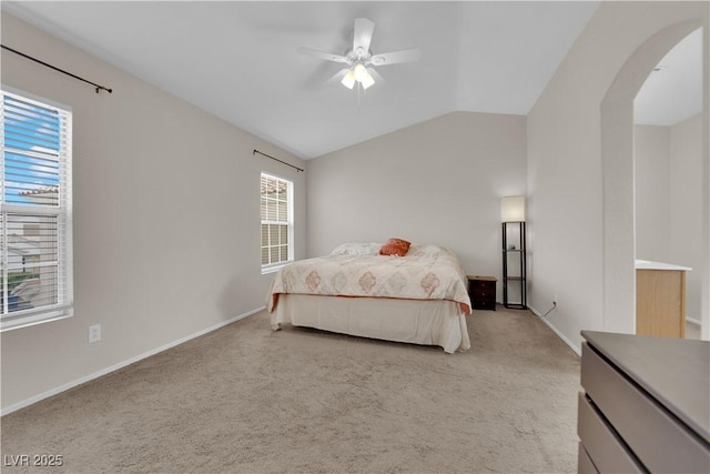 bedroom featuring light colored carpet, lofted ceiling, arched walkways, and ceiling fan