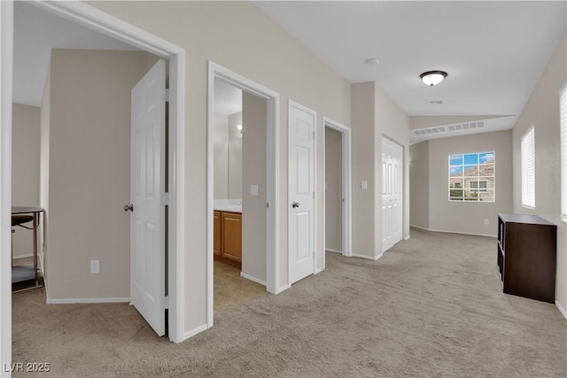 hall featuring light colored carpet, baseboards, and visible vents
