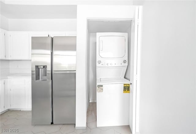 laundry area featuring estacked washer and dryer and light tile patterned flooring
