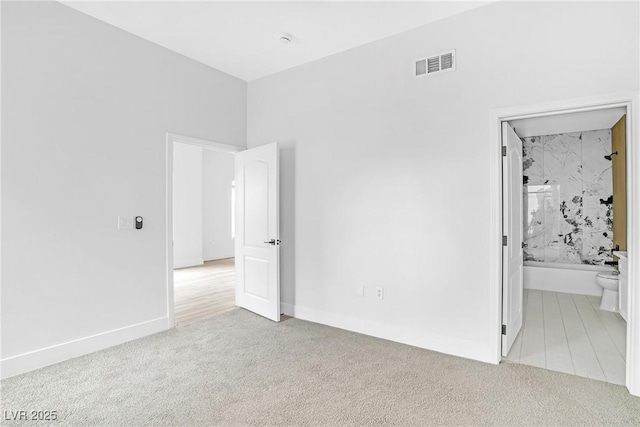 unfurnished bedroom with carpet floors, baseboards, and ensuite bathroom
