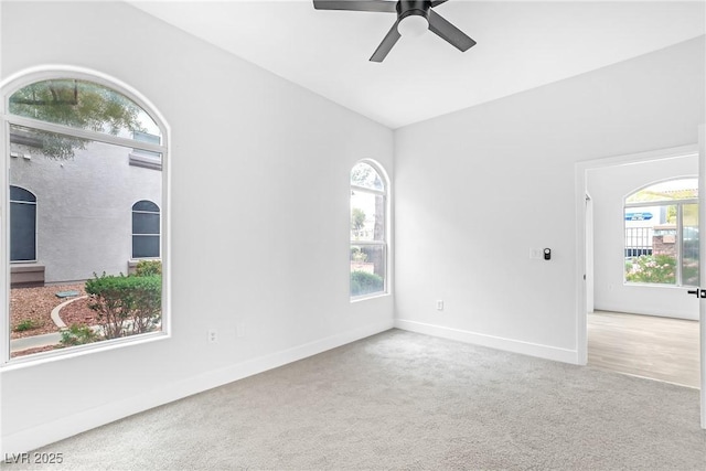 carpeted empty room featuring ceiling fan, baseboards, and vaulted ceiling