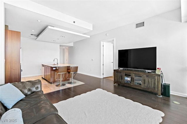 living room with baseboards, visible vents, and wood finished floors