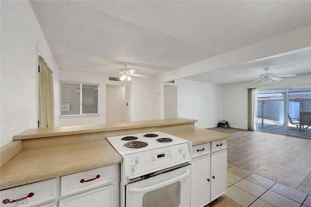 kitchen featuring electric range, a ceiling fan, open floor plan, a textured ceiling, and white cabinets