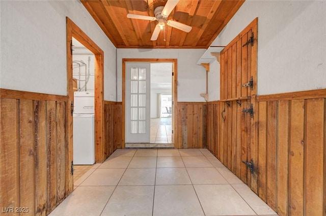 doorway to outside featuring a wainscoted wall, wood ceiling, ceiling fan, wood walls, and light tile patterned floors