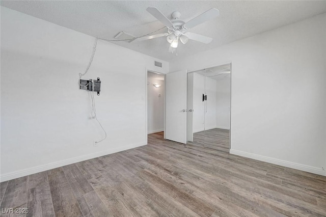 empty room with wood finished floors, ceiling fan, baseboards, and a textured ceiling