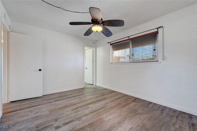 empty room with wood finished floors, ceiling fan, a textured ceiling, and baseboards