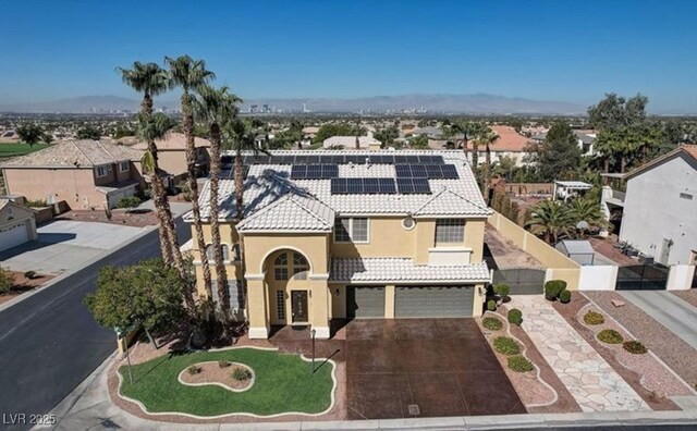 view of front of property featuring an attached garage, stucco siding, a tile roof, fence, and solar panels