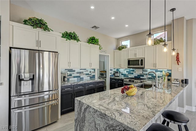 2625 Youngdale Dr, Las Vegas, NV 89134 - kitchen with stainless steel appliances, light stone countertops, backsplash, a breakfast bar area, and a peninsula