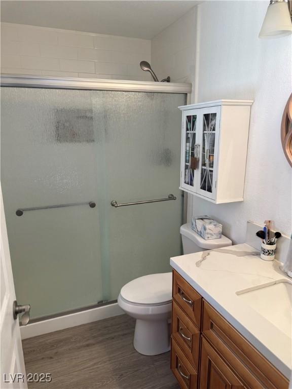 full bath with a stall shower, vanity, toilet, and wood finished floors