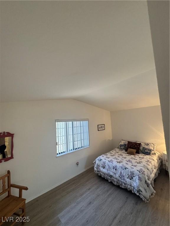 bedroom with baseboards, vaulted ceiling, and wood finished floors