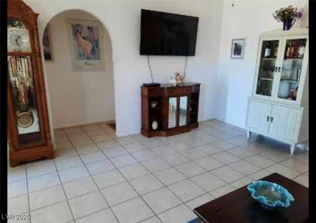 living area with arched walkways and light tile patterned flooring