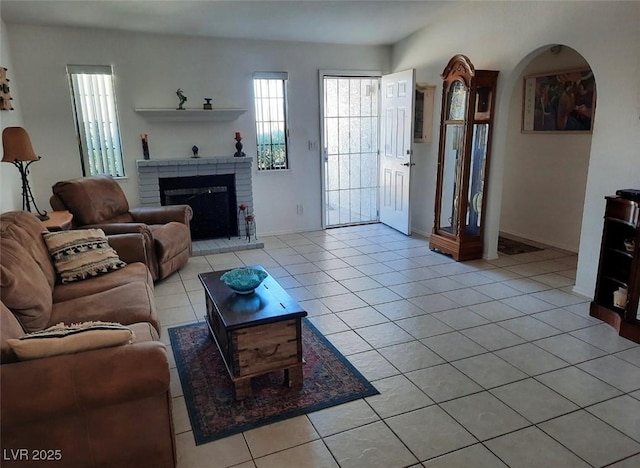 living room featuring light tile patterned floors, a brick fireplace, and baseboards