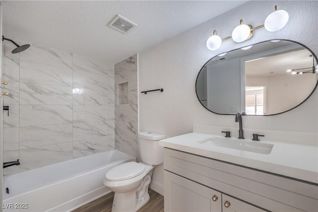 bathroom featuring toilet, wood finished floors, a textured ceiling, visible vents, and vanity