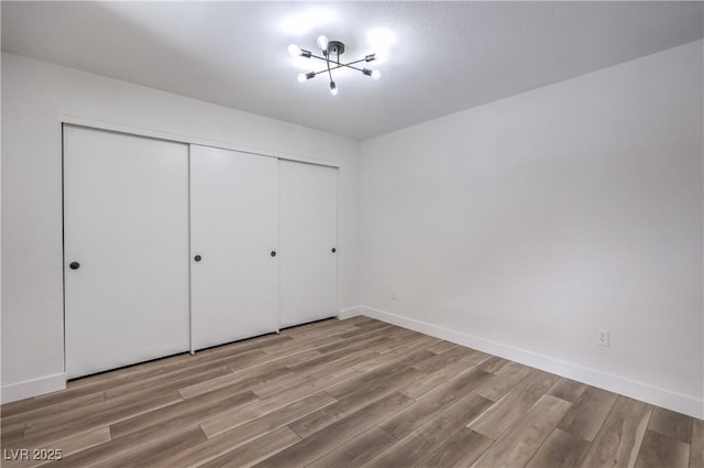 unfurnished bedroom featuring baseboards, a closet, and wood finished floors