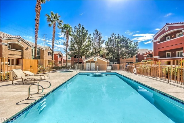 pool with a hot tub, fence, a patio area, and a residential view
