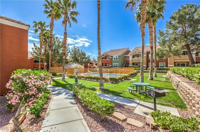 view of community with a lawn, a residential view, a pool, and fence