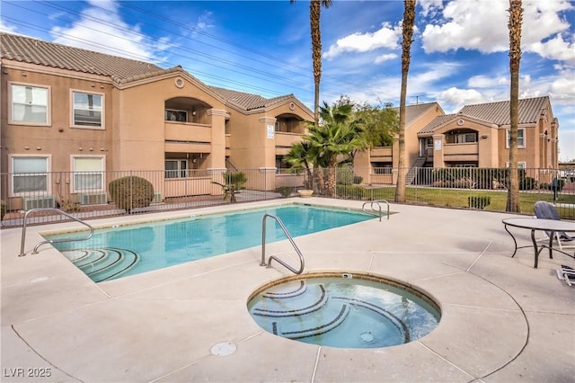 community pool with a hot tub, fence, and a patio