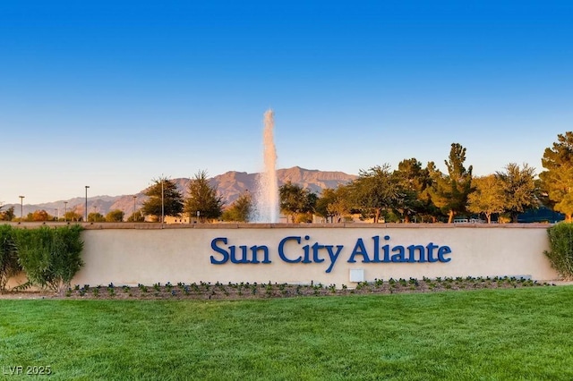 community / neighborhood sign featuring a mountain view and a yard