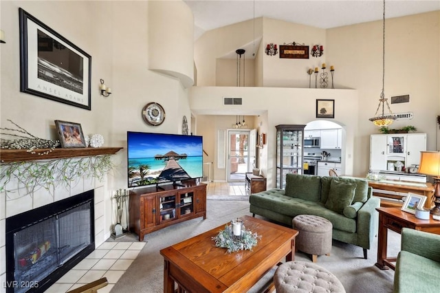 living area featuring light carpet, high vaulted ceiling, and a tile fireplace