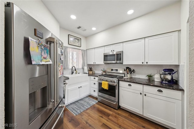 kitchen with stainless steel appliances, decorative backsplash, white cabinetry, dark wood-style floors, and recessed lighting