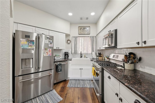 kitchen with appliances with stainless steel finishes, a sink, white cabinets, and recessed lighting