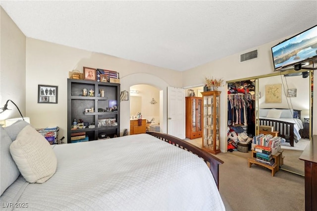 carpeted bedroom featuring arched walkways, a closet, and connected bathroom