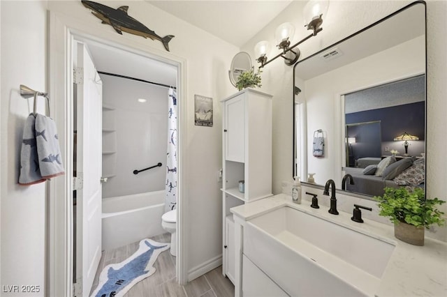 ensuite bathroom with toilet, vanity, shower / tub combo, wood finished floors, and baseboards