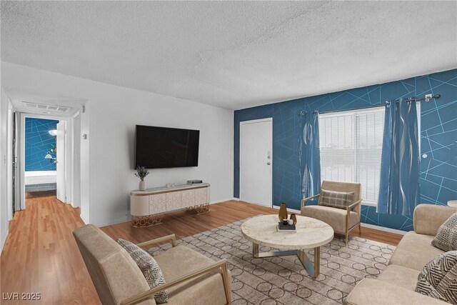 living area with a textured ceiling, wood finished floors, and tile walls