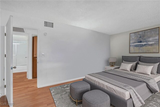 bedroom featuring light wood finished floors, a textured ceiling, and baseboards