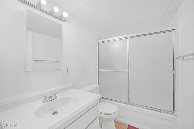 bathroom with toilet, vanity, and bath / shower combo with glass door