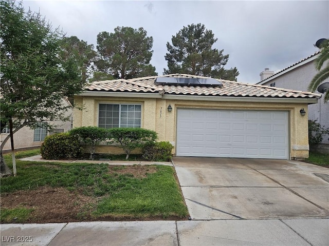 view of front of home featuring driveway, roof mounted solar panels, an attached garage, a tile roof, and stucco siding