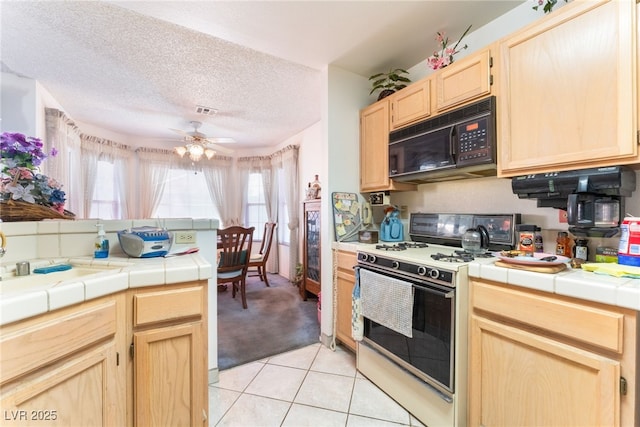 7617 Sea Cliff Way, Las Vegas, NV 89128 - kitchen featuring black microwave, white gas range oven, light brown cabinetry, tile countertops, and light tile patterned flooring