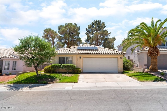 7617 Sea Cliff Way, Las Vegas, NV 89128 - view of front of property featuring a garage, a tiled roof, roof mounted solar panels, concrete driveway, and stucco siding