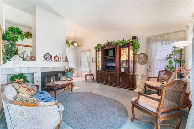 7617 Sea Cliff Way, Las Vegas, NV 89128 - carpeted living room with vaulted ceiling, a textured ceiling, and a tiled fireplace