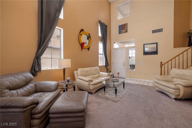 living area with carpet, plenty of natural light, visible vents, and a high ceiling