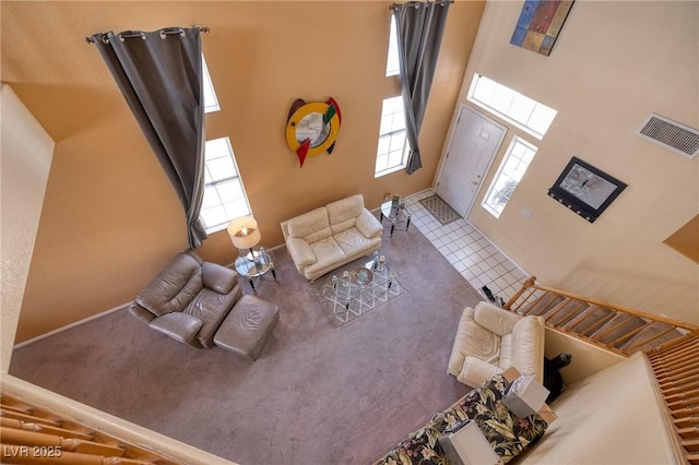 carpeted living room with a towering ceiling, baseboards, plenty of natural light, and visible vents