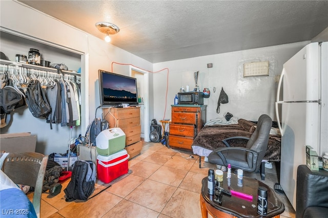 1708 Weeping Willow Ln, Las Vegas, NV 89104 - bedroom featuring freestanding refrigerator, a textured ceiling, a closet, and light tile patterned floors