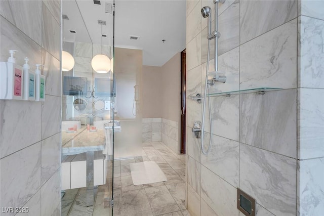 full bath featuring vanity, visible vents, and a tile shower